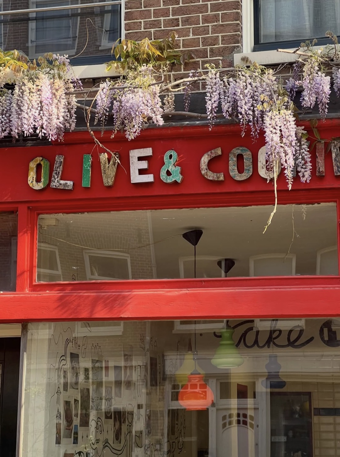 The red Olive & Cookie storefront with wisteria
